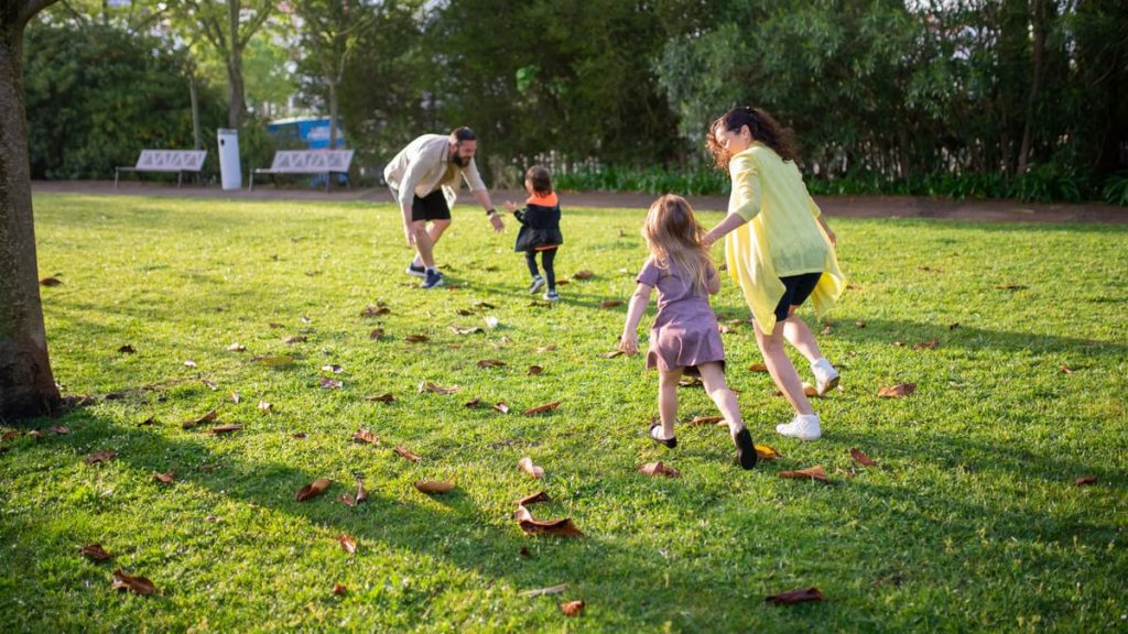 A joyful family playing together in a lush green park setting, enjoying a bright day.
